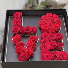 Red roses arranged in the shape of the letters L, O, V, and E in a black box