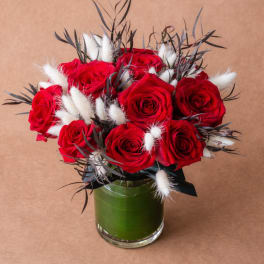 Red roses arranged in a glass vase with white fluffy accents