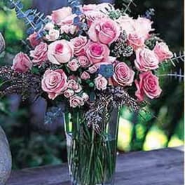 Tall vase of pink roses arranged in a rounded bouquet