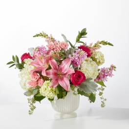 Pink lilies and roses arranged in a white vase