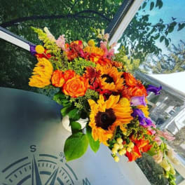 Bright bouquet of sunflowers, roses, and purple blooms in a vase