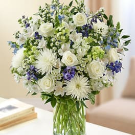 White and blue mixed bouquet in a clear glass vase