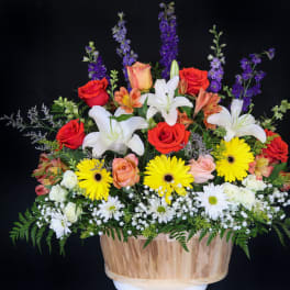 Mixed bouquet with roses, lilies, and daisies in a wooden basket