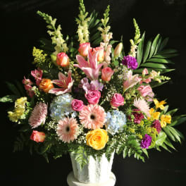 Mixed bouquet of roses, lilies, and gerbera daisies in a white vase