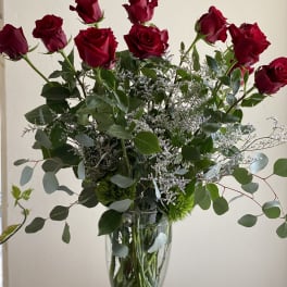 Red roses arranged in a clear glass vase with airy greenery.