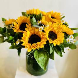 Bouquet of sunflowers with small white daisies in a glass vase