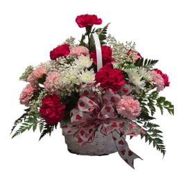 Basket arrangement of pink and white carnations with a heart ribbon