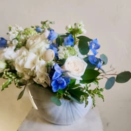 White and blue floral bouquet in a wrapped container