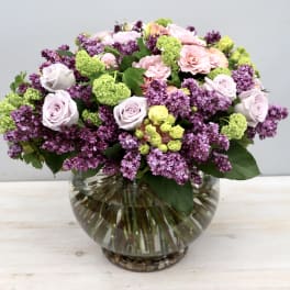 Bouquet of pink and purple flowers in a round glass vase