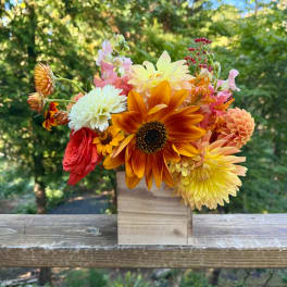 Mixed bouquet of orange, yellow, pink, and white flowers in a wooden box