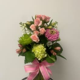 Pink roses and mixed blooms in a glass vase with a pink ribbon