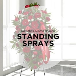 Standing spray of red flowers with a pink ribbon on an easel