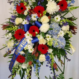 Large standing floral spray with red gerberas, white roses, and blue flowers