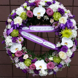 Heart-shaped floral wreath with purple ribbon and white orchids