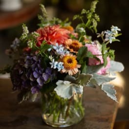 Mixed bouquet in a clear glass vase with pink, orange, purple, and blue flowers