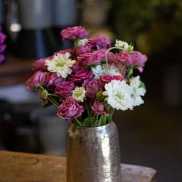 Pink roses and white daisies arranged in a silver vase