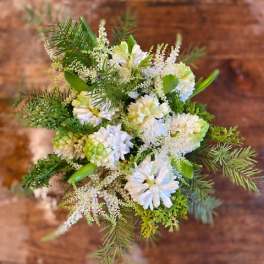 White floral bouquet with green accents and pine branches