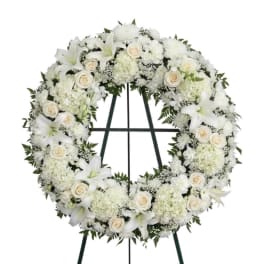 White funeral wreath with lilies, roses, and chrysanthemums on a stand