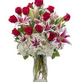 Bouquet of red roses and pink lilies in a clear glass vase