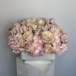 Pink roses and carnations arranged in a white rectangular vase