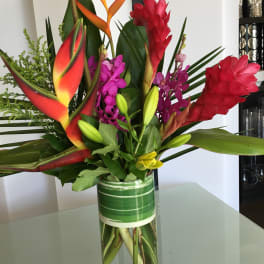 Tropical bouquet with red heliconia and purple orchids in a glass vase