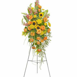 Tall floral standing spray with orange roses and yellow sunflowers on a metal easel