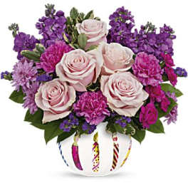 Pink roses and purple flowers arranged in a decorated white vase