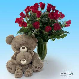 Red roses in a glass vase with two teddy bears in front