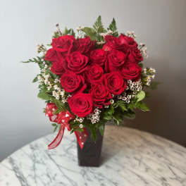 Red roses arranged in a black vase with a red ribbon