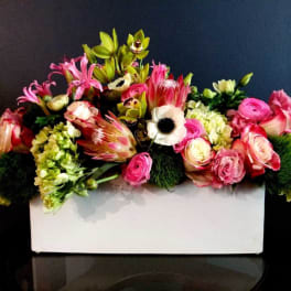 Mixed pink and green floral arrangement in a white rectangular container