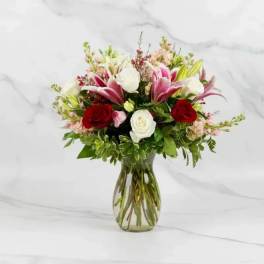Bouquet of red and white roses with pink lilies in a glass vase