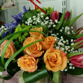 Orange roses and pink tulips in a wooden box with white filler flowers