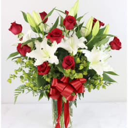 Bouquet of red roses and white lilies in a glass vase with a red ribbon