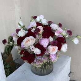 Bouquet of red and blush roses with pale lisianthus in a glass vase