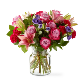 Mixed bouquet of pink and purple roses with lilies in a glass vase