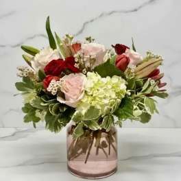 Mixed roses and hydrangea in a pink glass vase