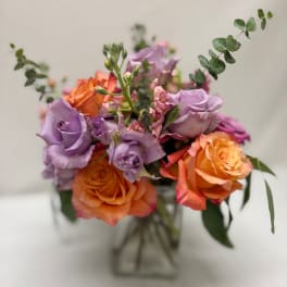 Bouquet of lavender and orange roses in a clear vase