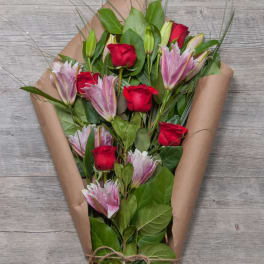 Bouquet of red roses and pink lilies wrapped in brown paper