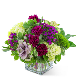 Mixed bouquet of magenta and green flowers in a clear glass cube vase