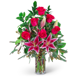 Pink roses and lilies arranged in a clear glass vase