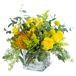 Yellow floral arrangement in a clear square glass vase