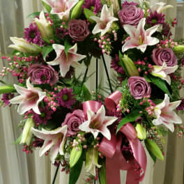 Heart-shaped floral wreath with pink lilies and roses on a stand