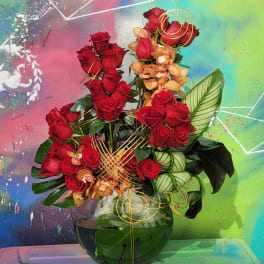 Red roses and peach orchids in a glass vase with gold wire accents