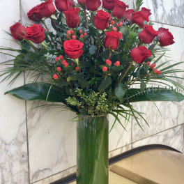 Tall vase arrangement of red roses with greenery