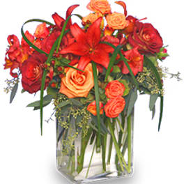 Red and orange floral arrangement in a clear glass vase