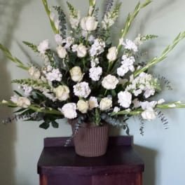 White floral arrangement in a ribbed vase with tall green spikes