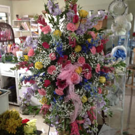 Large mixed floral standing arrangement with pink ribbon