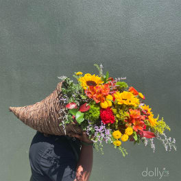 Large mixed bouquet in a woven basket with sunflowers and orange blooms