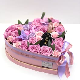 Heart-shaped box of pink and lavender roses with a mini Moët bottle