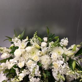Large white floral arrangement with roses, lilies, and orchids